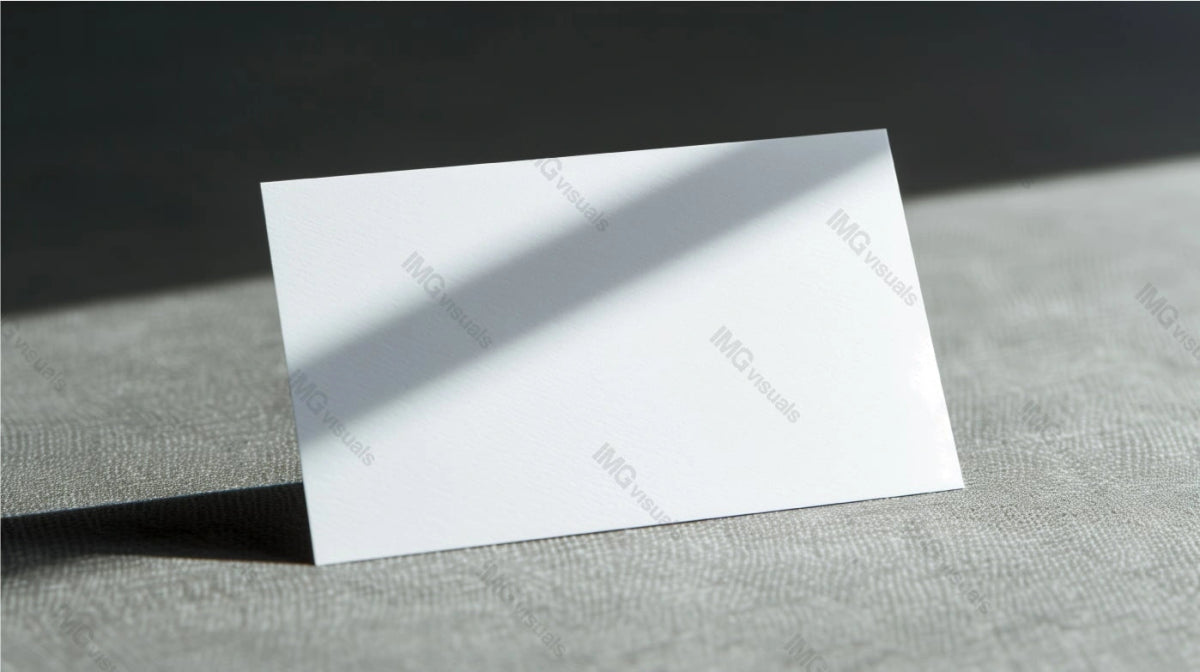 Blank white card mockup stands on light grey surface with dramatic shadow, ai generated. Modern minimalist setting. Businesscard template advertising image. Stationary mock up product photorealistic