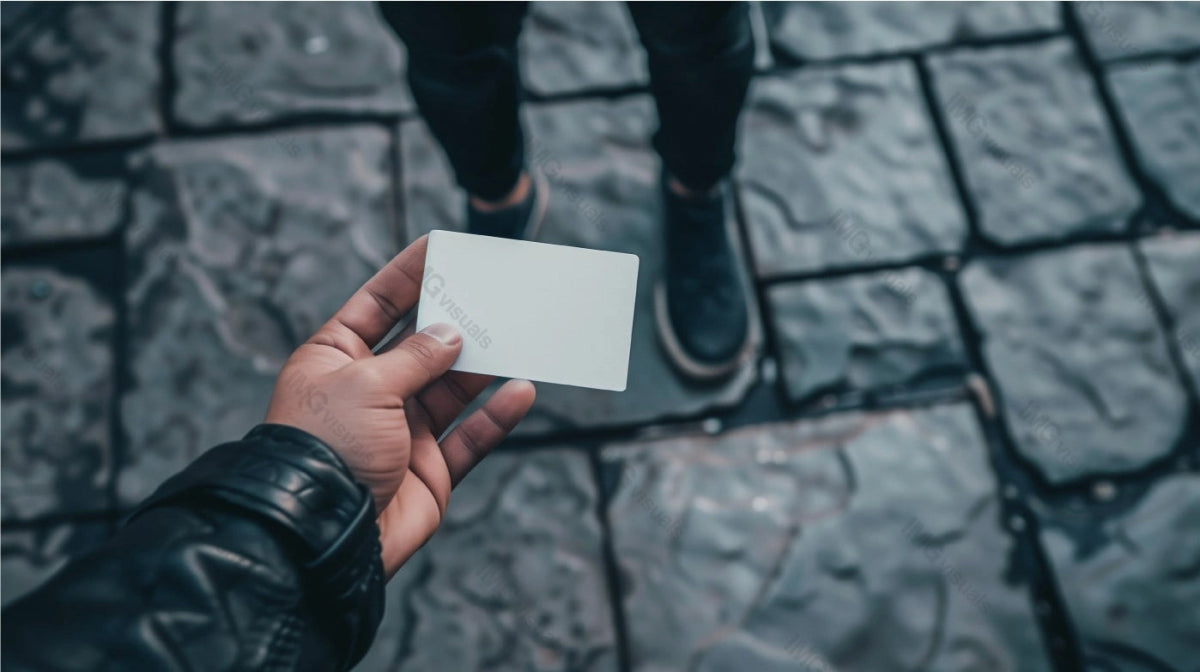 Person holds blank white card mockup against stone-paved street, ai generated. Casual urban setting. Businesscard template advertising image. City scene. Professional mock up product photorealistic